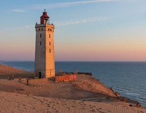 A lighthouse on a sandy beach with the ocean in the background. - 6 Person Holiday Home in Hjorring (Hjørring)
