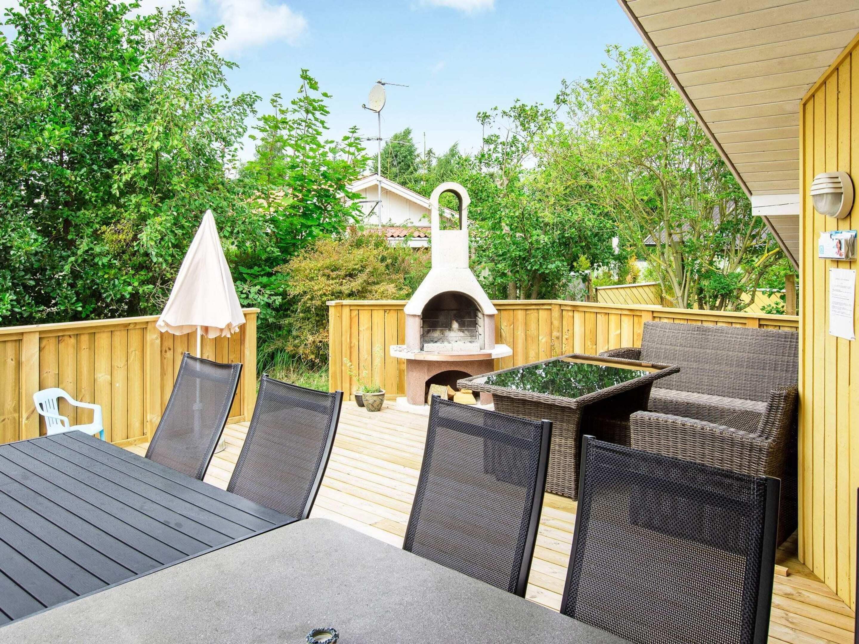 Patio esterno con barbecue, mobili in vimini e un pontile in legno.