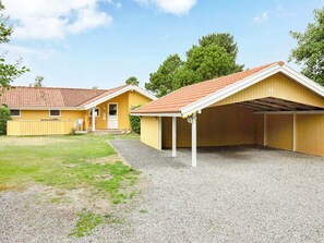 A row of yellow cabins with red-tiled roofs, gravel ground, and a grassy area. - 4 Star Holiday Home in Vaeggerlose (Vaeggerlose)