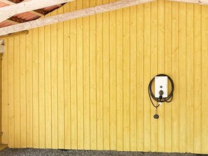 A room with a wooden wall and a power outlet with a cable.