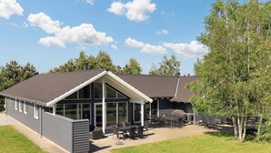A modern building with a large patio area, outdoor seating, and a covered section. - Luxury Holiday Home in Falster near Sea (Vaeggerlose)