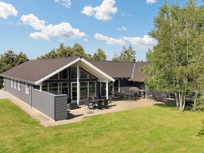 A modern building with a large patio area, outdoor seating, and a covered section. - Luxury Holiday Home in Falster near Sea (Vaeggerlose)