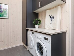 A laundry area with a washing machine, a potted plant, and a towel with a deer design. - Luxury Holiday Home in Falster near Sea (Vaeggerlose)