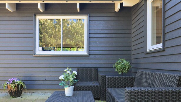 A patio with wicker furniture, a potted plant, and a window with a view of trees. - Luxury Holiday Home in Falster near Sea (Vaeggerlose)