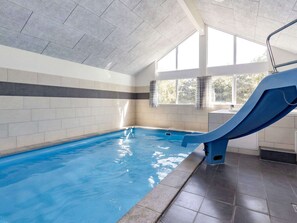 An indoor swimming pool with a blue slide, tiled walls, and large windows. - Luxury Holiday Home in Falster near Sea (Vaeggerlose)