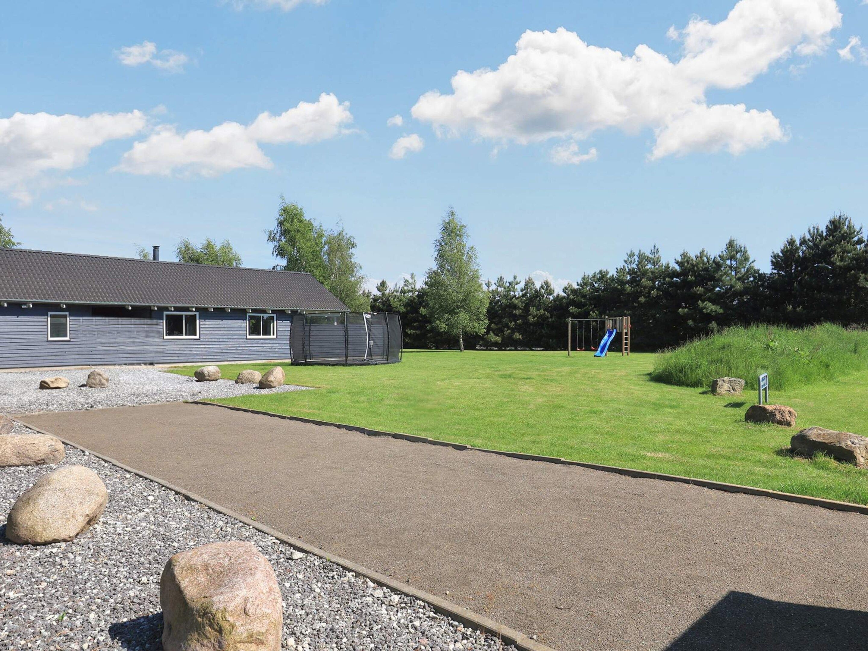 A residential property with a house, a playground with a slide, and a gravel driveway.