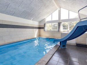 An indoor swimming pool with a blue slide, tiled walls, and large windows. - Luxury Holiday Home in Falster near Sea (Vaeggerlose)