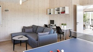 A modern living room with a blue ping pong table, grey sofa, and a white desk with a computer. - Luxury Holiday Home in Falster near Sea (Vaeggerlose)