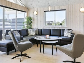 A modern living room with a sectional sofa, two armchairs, a round coffee table, and a potted plant. - Luxury Holiday Home in Falster near Sea (Vaeggerlose)