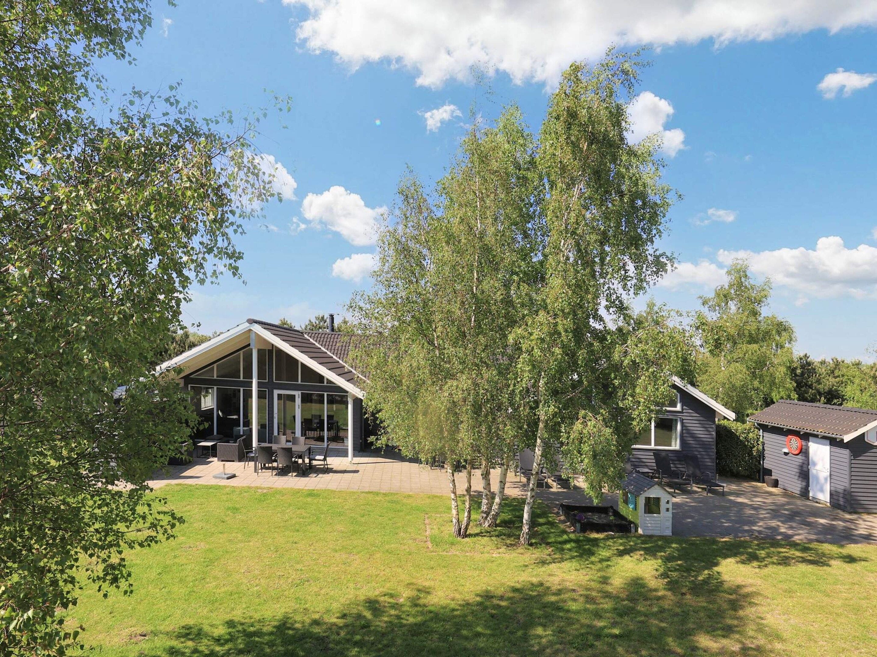 A modern house with a glass-enclosed patio, a small deck, and a well-maintained lawn.