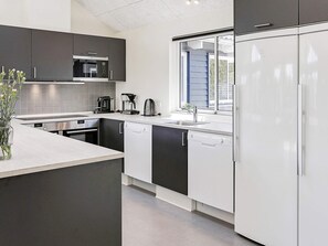 A modern kitchen with a built-in microwave, coffee maker, and dishwasher. - Luxury Holiday Home in Falster near Sea (Vaeggerlose)