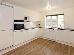 A modern kitchen with white cabinetry, a built-in oven, microwave, and dishwasher.