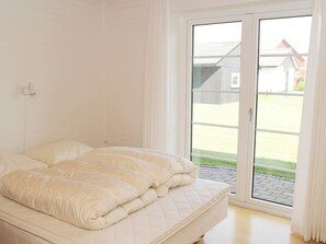 Un dormitorio con cama, ventana y vista al exterior.