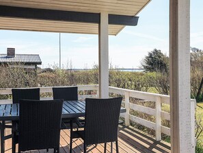 A covered outdoor seating area with a table and chairs, overlooking a natural landscape. - 5 Star Holiday Home in Spottrup (Spøttrup)