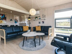 A modern living room with a sectional sofa, two round tables, and a large window with a view. - 5 Star Holiday Home in Spottrup (Spøttrup)
