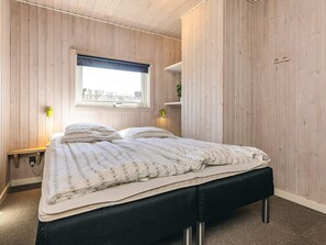 A bedroom with a bed, a window, a bedside table, and a wall-mounted shelf. - 5 Star Holiday Home in Spottrup (Spøttrup)