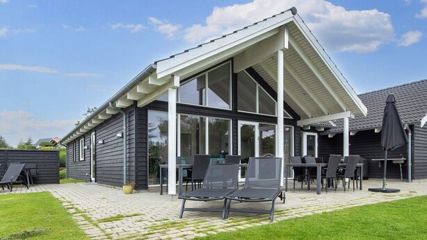 Eine moderne Terrassenanlage im Freien mit überdachter Sitzgelegenheit, Grill und gepflegtem Rasen.