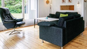 A room with a dark green sofa, a black leather chair, a white table, and a wooden floor. - 8 Person Holiday Home in Hojslev-by Traum (Hojslev)