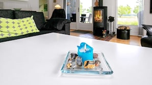 A modern living room with a white sofa, a glass table with stones, and a blue candle. - 8 Person Holiday Home in Hojslev-by Traum (Hojslev)