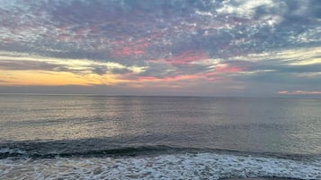 A beach with waves and a cloudy sky.