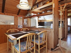A wooden interior with a dining table, chairs, a hanging light fixture, and a kitchen area. - 6 Person Holiday Home in Hvide Sande (Hvide Sande)