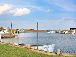 A marina with several boats docked, a grassy area in the foreground, and a clear sky. - 6 Person Holiday Home in Hvide Sande (Hvide Sande)