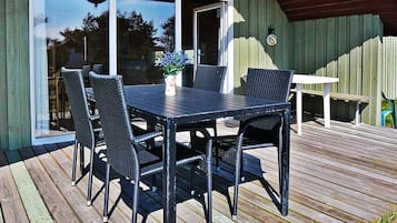 A deck with a table and chairs, a potted plant, and a sliding glass door.