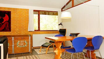 Un comedor con una mesa de madera, sillas azules, una lámpara colgante blanca y un radiador.