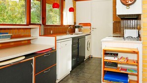 A kitchen with a dishwasher, sink, and a coffee maker. There are red pendant lights and a copper pot on the wall. - 4 Star Holiday Home in Nexo (Nexø)