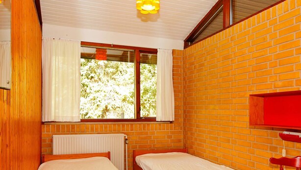 A room with two wooden beds, a red chair, a window with curtains, and a red shelf. - 4 Star Holiday Home in Nexo (Nexø)
