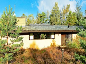 A single-story house with a sloped roof, surrounded by dense vegetation and trees. - 4 Star Holiday Home in Nexo (Nexø)