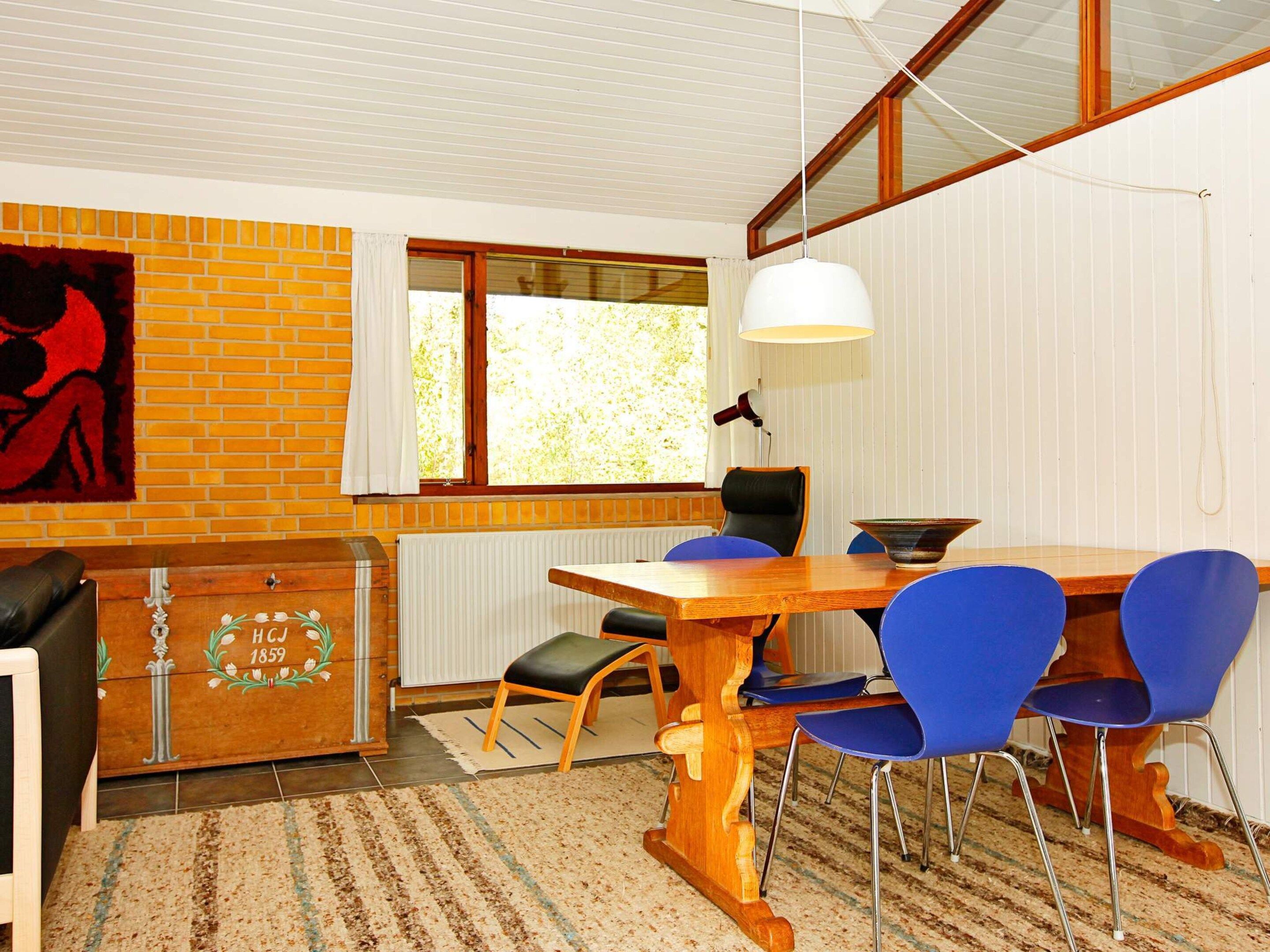 A dining area with a wooden table, blue chairs, a white pendant light, and a radiator.