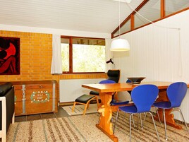 Et spiseområde med et træbord, blå stole, en hvid hængende lampe og en murstensvæg med et vindue.
