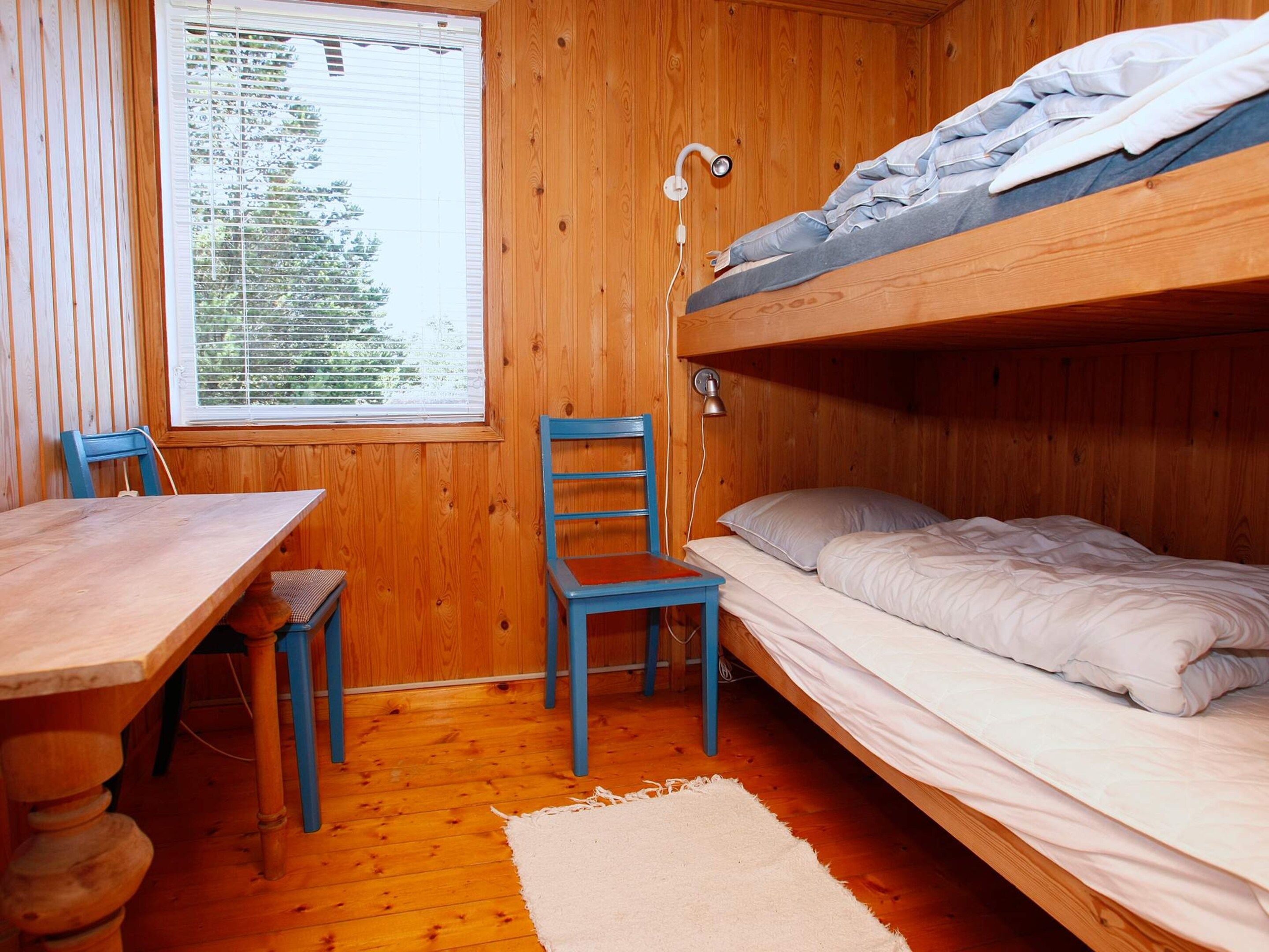 Une pièce en bois avec des lits superposés, un bureau et une chaise.
