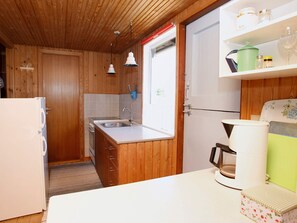 A compact kitchen with wooden cabinets, a white countertop, a sink, and a coffee maker.