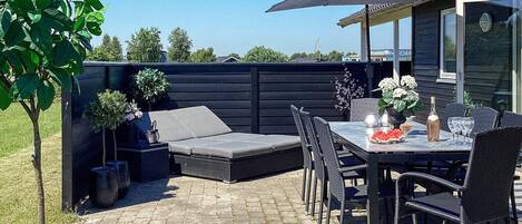 An outdoor patio with a dining table, chairs, and a large umbrella.