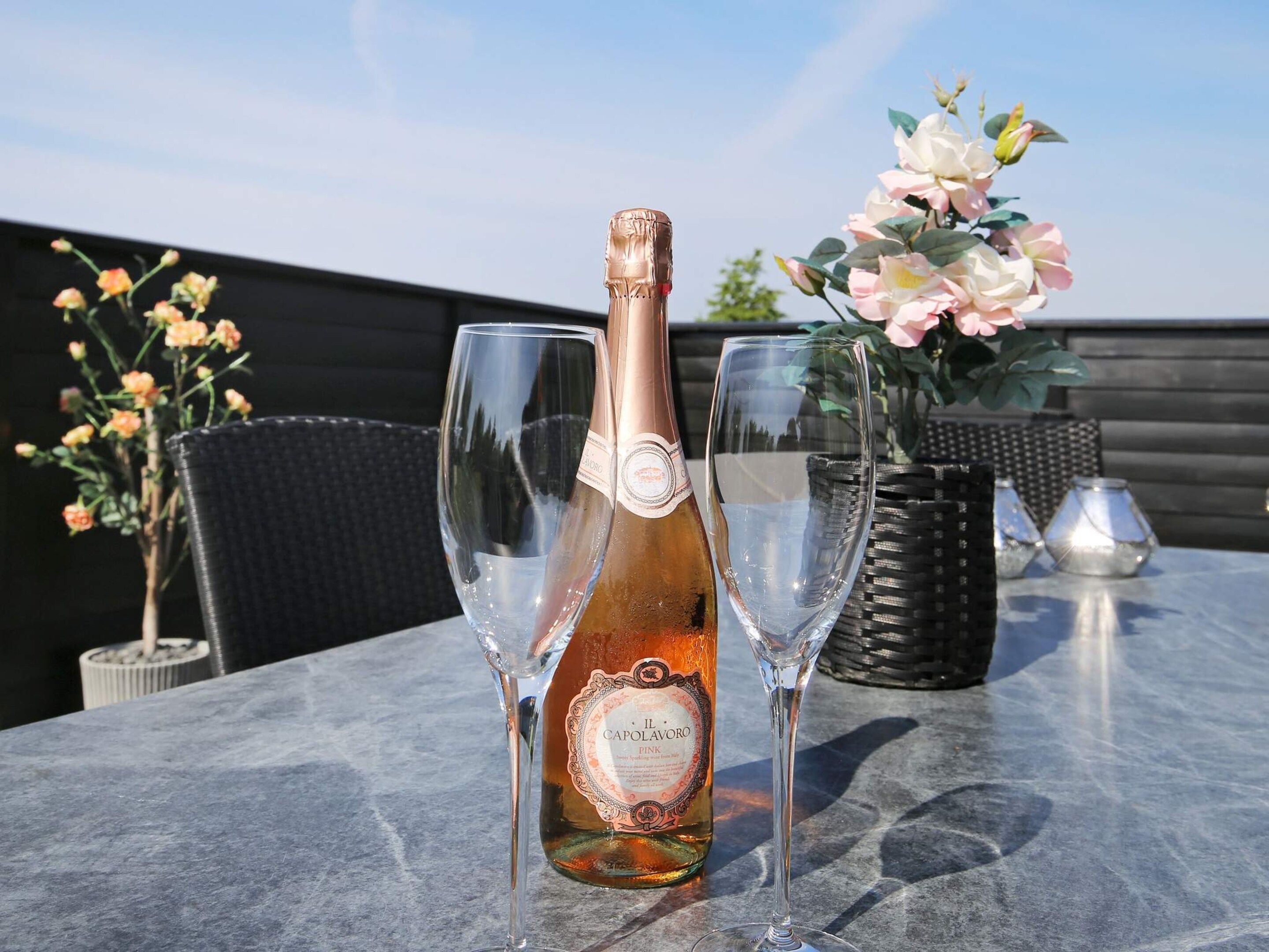 Una botella de vino rosado Il Capovolavo sobre una mesa con dos copas de vino.