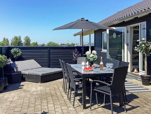 An outdoor patio with a table, chairs, a sofa, and a large umbrella. - 4 Star Holiday Home in Vaeggerlose (Vaeggerlose)