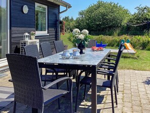 An outdoor patio with a table and chairs, a small garden, and a play structure. - 4 Star Holiday Home in Vaeggerlose (Vaeggerlose)