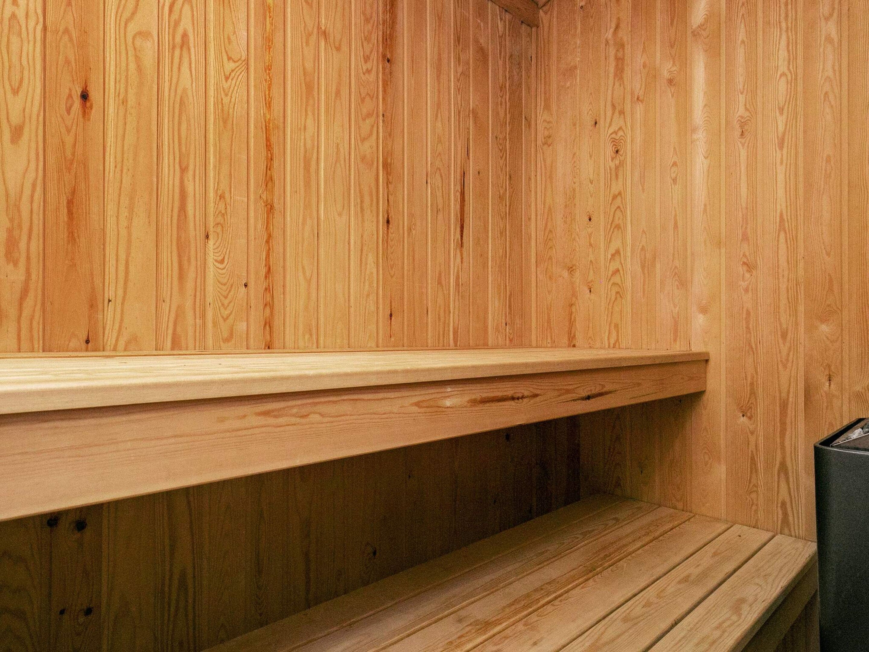 A wooden interior with a bench and a shelf.