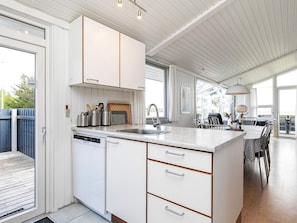A modern kitchen with white cabinetry, a built-in dishwasher, and a large island with a sink.
