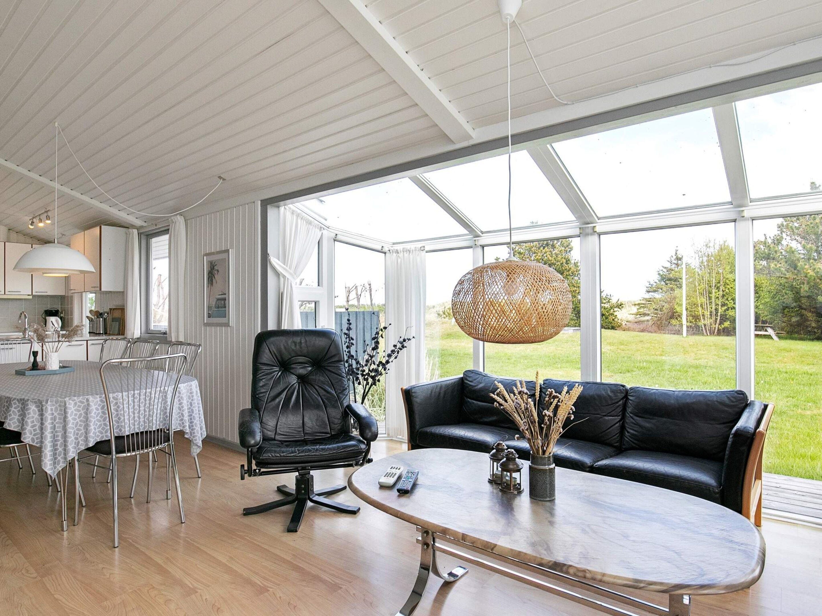 A modern living room with a dining area, large windows, and a view of the outdoors.