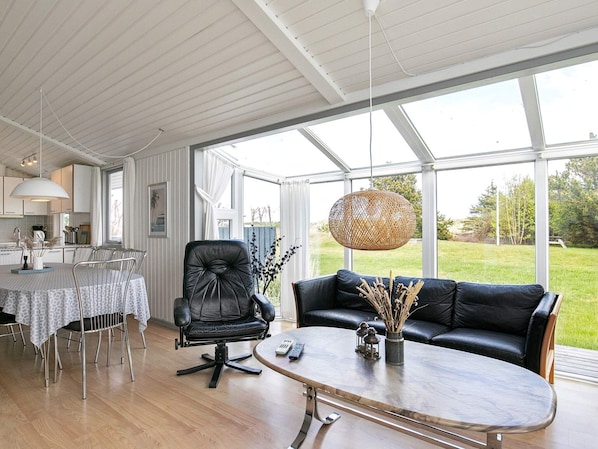 A modern living room with a dining area, large windows, and a view of the outdoors.