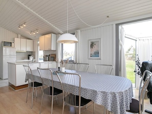 A modern kitchen with white cabinets, a microwave, and a dining area with a table and chairs.