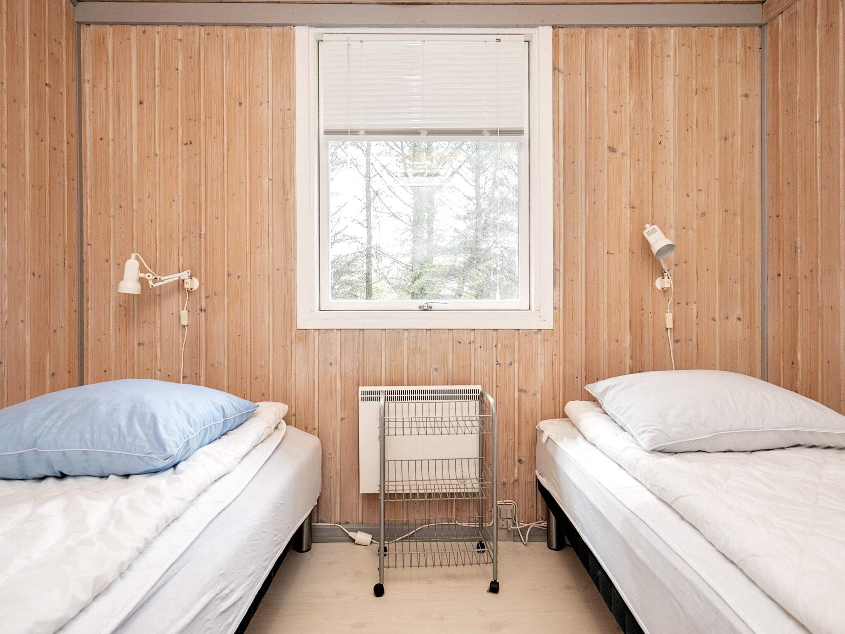 Une chambre avec deux lits, une fenêtre et un radiateur.