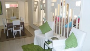 Ein modernes Wohnzimmer mit Essbereich, weißen Möbeln und einem grünen Teppich.