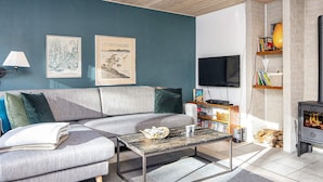 A modern living room with a grey sofa, a coffee table, a fireplace, and two framed artworks on the wall. - 5 Person Holiday Home in Hemmet (Hemmet)
