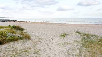 A sandy beach with a rocky shoreline and a clear sky.