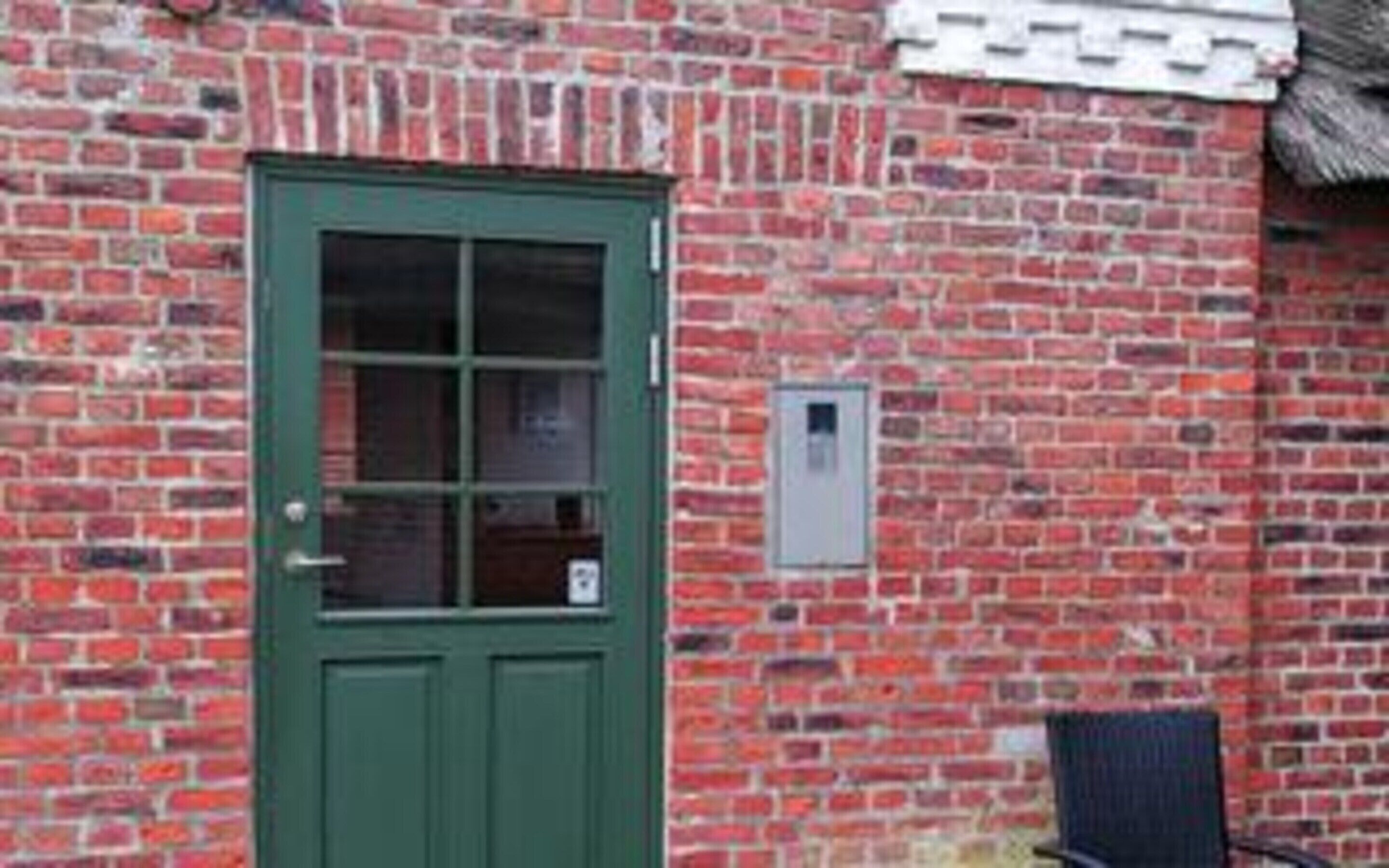 A brick building with a green door and a small window.
