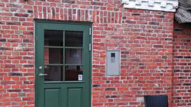 Ein Backsteinhaus mit grüner Tür und kleinem Fenster.